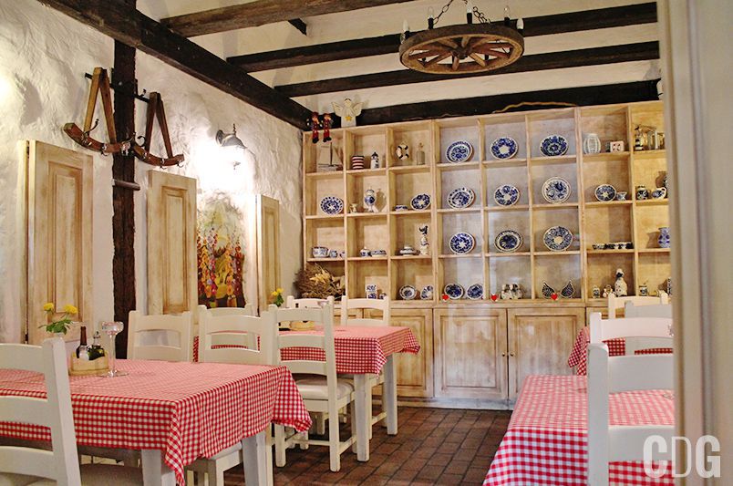 Sala restauracji z białymi stolikami i obrusami w czerwoną kratę