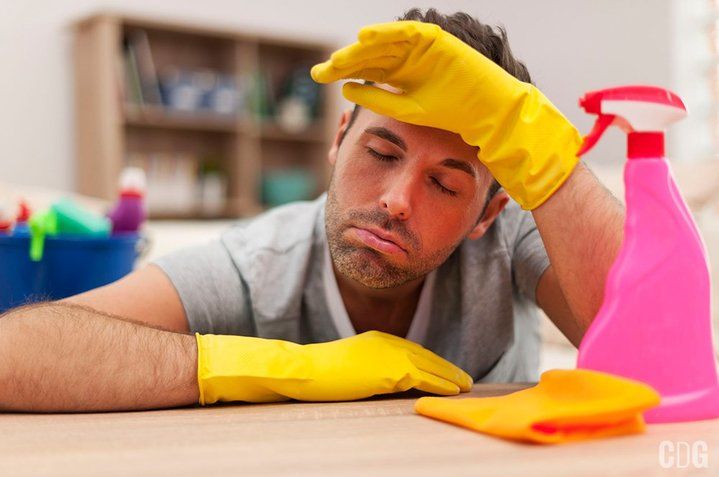 Mężczyzna w gumowych rękawiczkach zmęczony sprzątaniem