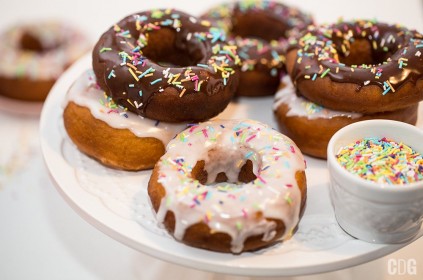 Donuty, pączki amerykańskie w lukrowej i czekoladowej polewie przyozdobione kolorowymi posypkami