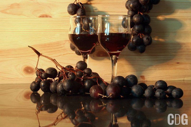 Kieliszki z czerwonym winem pośród ciemnych winogron