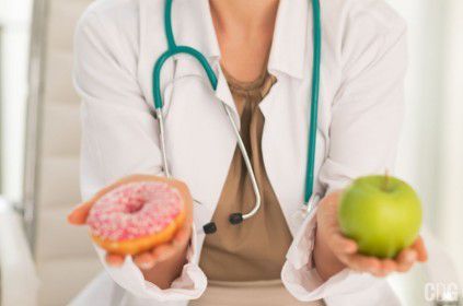 Pączek i jabłko w dłoniach lekarza