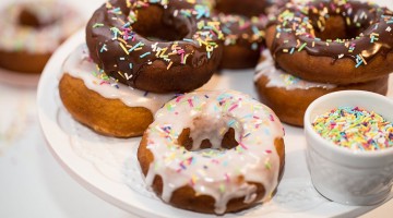 Donuty, pączki amerykańskie w lukrowej i czekoladowej polewie przyozdobione kolorowymi posypkami