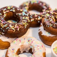 Donuty, pączki amerykańskie w lukrowej i czekoladowej polewie przyozdobione kolorowymi posypkami , zdjęcie główne