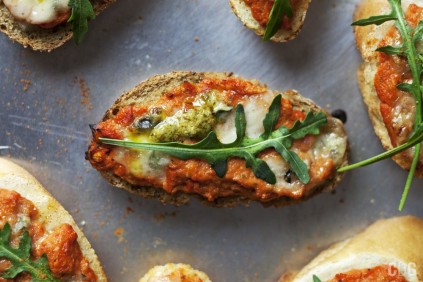 bruschetta ze świeżym pesto z bazylii oraz pulpą pomidorową ozdobiona listkiem rukoli