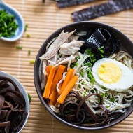 Zupa Ramen w miseczce z jajkiem, makaronem, marchewką, mięsem, grzybami i glonami. Kadr z góry