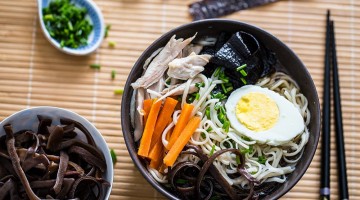 Zupa Ramen w miseczce z jajkiem, makaronem, marchewką, mięsem, grzybami i glonami. Kadr z góry