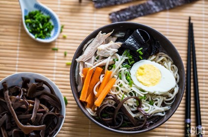 Zupa Ramen w miseczce z jajkiem, makaronem, marchewką, mięsem, grzybami i glonami. Kadr z góry