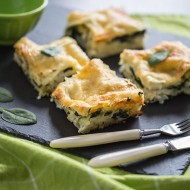 Lasagne z dorszem i szpinakiem na czarnym kamieniu. Wszystko znajduje się na zielonej serwetce.